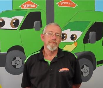 Male SERVPRO employee standing in front of green SERVPRO truck