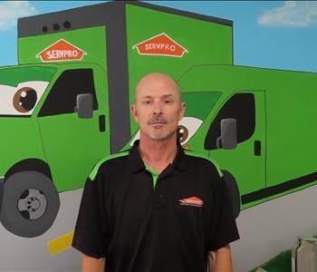 Male SERVPRO employee standing in front of green truck.