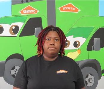Female SERVPRO employee standing in front of green SERVPRO truck. 