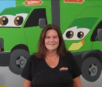 Female SERVPRO employee standing in front of green SERVPRO truck. 