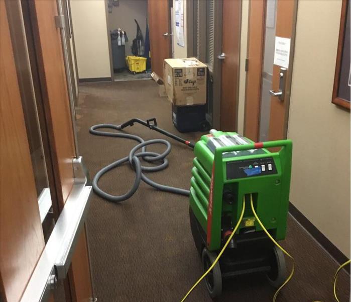 Servpro cleaning equipment on wet carpet in office. 