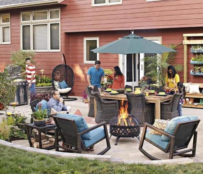 People gathering in backyard around a fire pit having a get together