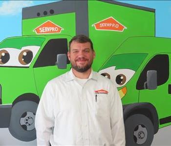 Male SERVPRO employee standing in front of green SERVPRO truck. 